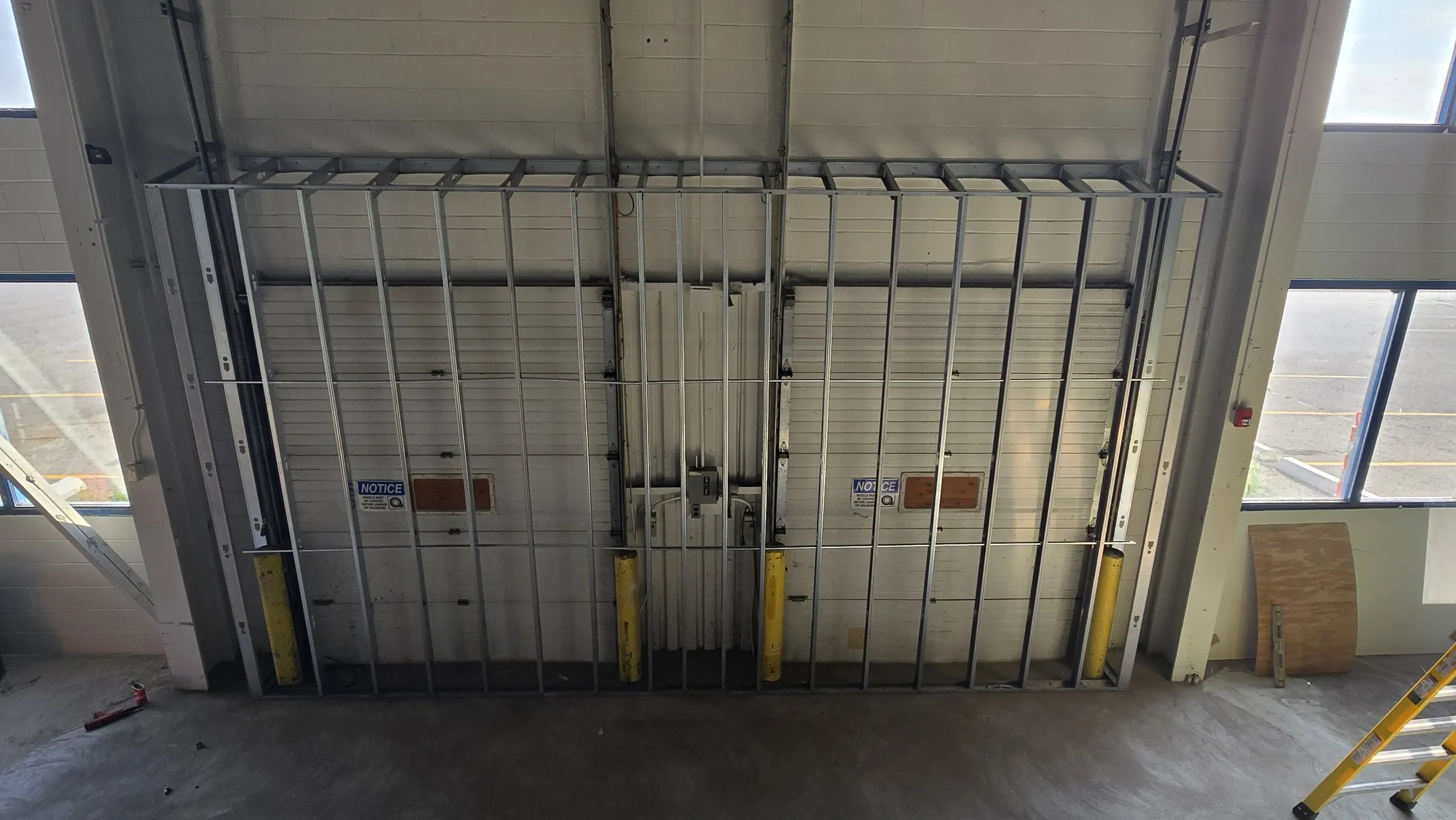 Steel stud wall framed in front of two overhead doors