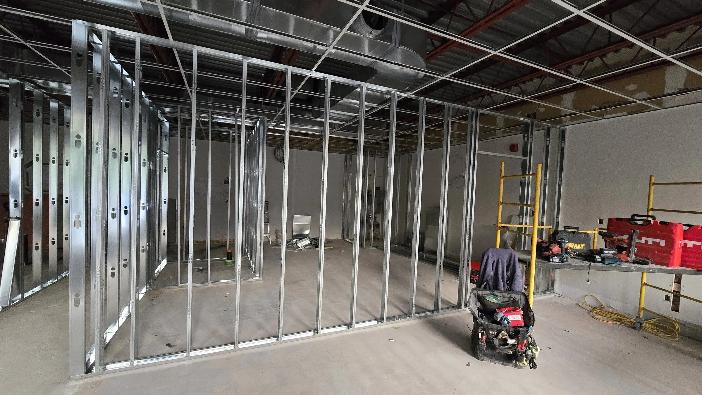 Wide view of framed office walls with tools staged on a scaffold