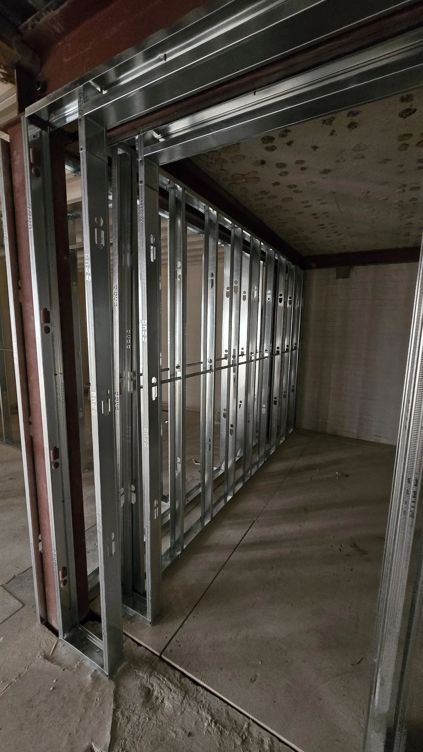 Steel stud walls forming a corridor beside an existing steel beam